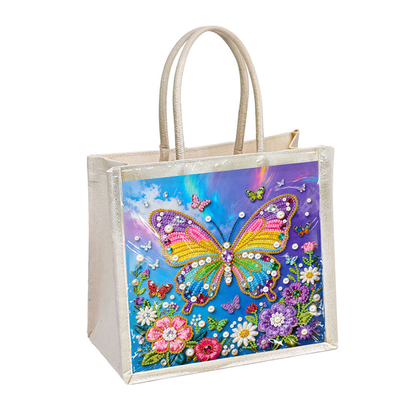 A cream-colored canvas tote bag with a clear vinyl front cover featuring a colorful diamond painting design of a butterfly and flowers, set against a plain white background.
