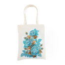 An off-white canvas tote bag featuring a detailed floral design of blue and teal roses with gold and brown leaves, set against a plain white background.