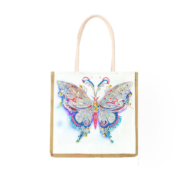 A white canvas tote bag with a natural jute trim and light beige handles, featuring a large, colorful beaded butterfly design on the front.