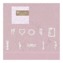 A sheet of white decorative embossed paper with various white lace-like and floral border designs, presented on a dusty pink background with a brand label at the top.