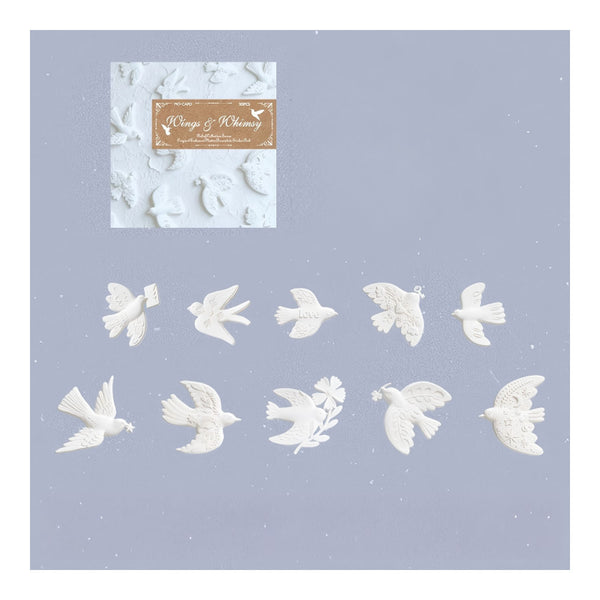White bird-shaped nail art stickers or decals arranged on a light lavender background, with a small branded sample card in the upper left reading Wings & Whims.