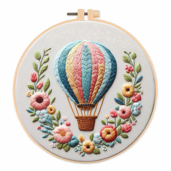 Embroidered circular wall art in a wooden hoop, featuring a colorful hot air balloon surrounded by delicate flowers on a white background.