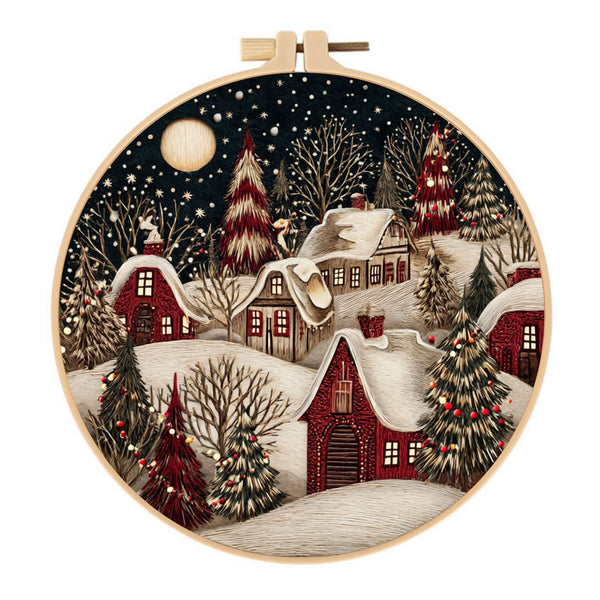 Embroidery hoop with a winter village scene featuring snow-covered houses and trees.