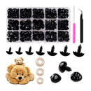 A set of black plastic hair claw clips shown in a clear organizer tray, with several individual clips displayed below, beige elastic loops, a pink-handled tool, and a black-handled tool on a white background. A small plush teddy bear is also included in the arrangement.