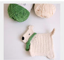 Crocheted dog toy with green scarf next to green and beige yarn on a light background