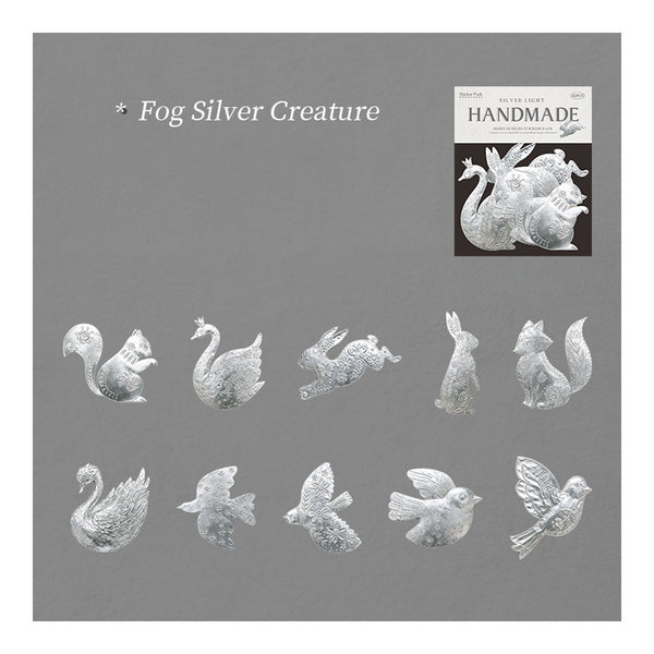 A gray square card showing the name 'Fog Silver Creature' at the top left, a small inset photo labeled 'HANDMADE' at top right, and multiple small silver animal and bird figurines arranged across the lower half. The product appears to be a collection of silver creature/craft pieces shown in a catalog-style layout.