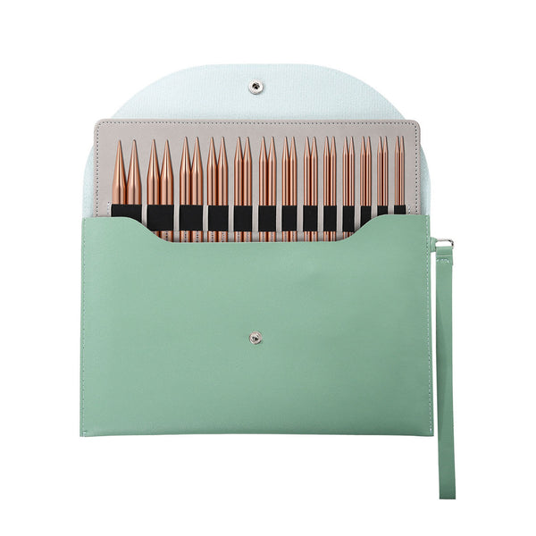 A mint green leatherette needle case shown open on a white background, containing multiple rose gold knitting needles with black bands.