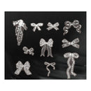 A set of silver metallic ribbon-shaped embellishments or charms arranged on a black fabric background.