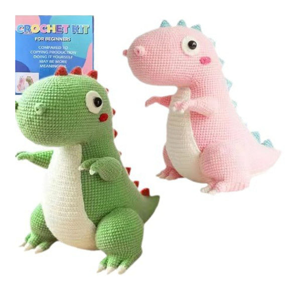 Two crocheted dragons, one green and one pink, with a crochet kit in the background.