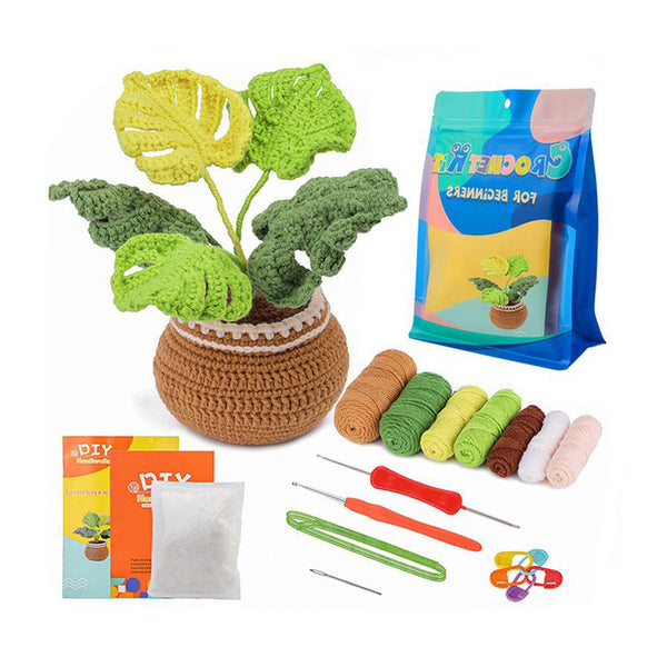 Crocheted potted plant kit with a handmade green plant in a brown basket, a blue and pink bag of crochet hooks, yarn balls in green, yellow, brown, pink, and white, crochet needles, a small booklet, and a packet on a white background.