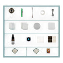 A flat-lay product shot of a DIY wax melt or candle making kit containing various small tools and ingredients, arranged in a grid on a white background with a light blue border.