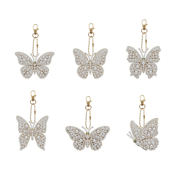 Six butterfly-shaped drop earrings in gold-tone metal pavé-set with clear stones, arranged in two rows of three on a plain white background.