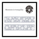 A product display card for 'Blossoms in tranquility' washi tape by Agile. The card features a black border, the product name in black text, a circular black logo with white floral details, and two horizontal strips of the silver glitter tape showing a white cherry blossom pattern.