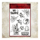 A sheet of clear stamp designs featuring Halloween-themed illustrations including a haunted house, spiderwebs, bats, a full moon, a tombstone, and spooky text, shown on a red backing card against a textured beige background.
