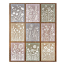 A 3x3 grid of nine square floral stencil sheets arranged in a wooden frame. Each stencil features a different muted background color including gray, pink, green, and beige, with white cut-out designs of wildflowers, leaves, and butterflies.