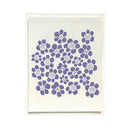 A square art print or card featuring a cluster of purple hand-drawn style flowers on a warm off-white background, presented in a thin white frame against a clean white backdrop.