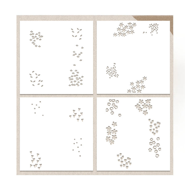 Four square white sheets arranged in a 2x2 grid on a light beige background, each printed with small decorative floral and leaf motifs in a warm taupe tone.