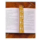 A gold-toned metal saxophone rests on top of two open book pages against a dark brown textured background.