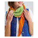 Person wearing a colorful knitted scarf with a plain background