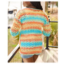 A woman wearing a colorful striped open-knit sweater, photographed from the back on a balcony with outdoor scenery in the background.