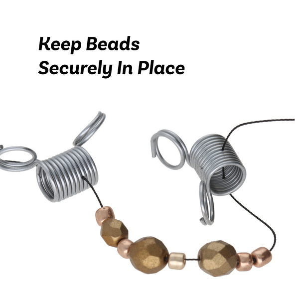 A pile of small silver metal spring clamps with attached jump rings, shown on a plain white background.