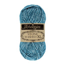 A skein of Scheepjes Stone Washed XL yarn in a heathered blue color, featuring a paper label with the brand name Scheepjes.