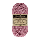 A skein of Scheepjes Stone Washed XL yarn in a dusty rose pink color, featuring its original paper label, set against a plain white background.