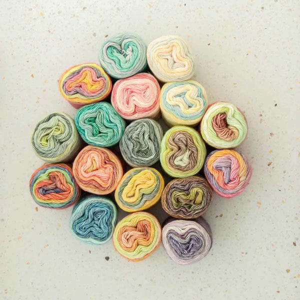 Assorted colorful yarn rolls on a textured surface