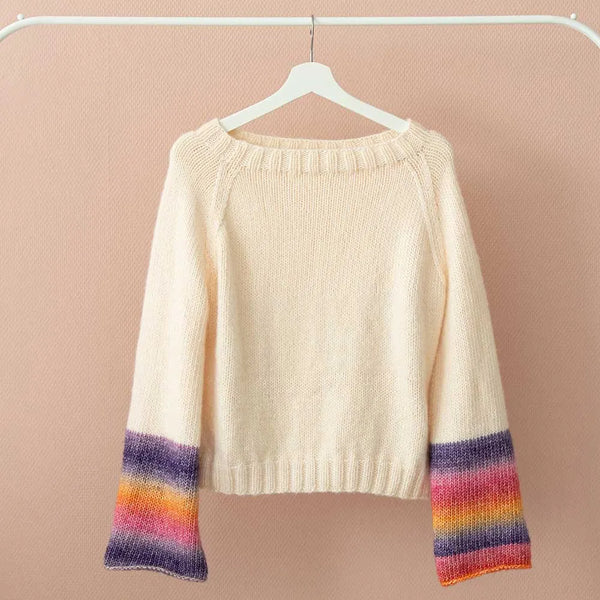 Cream-colored knit sweater with colorful striped cuffs, hanging on a white hanger against a soft pink background.