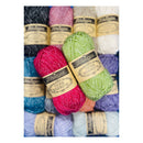 Four skeins of Scheepjes Stonewashed X-L yarn in bright pink, light green, lavender, and navy, arranged in front of a background of more yarn skeins in various colors.