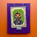 A square Halloween greeting card featuring a carved jack-o'-lantern head in a tuxedo with a purple bow tie, set against a purple damask patterned background. The card has a gold ornate frame border and the text 'happy haunting' at the bottom, displayed on an orange background.