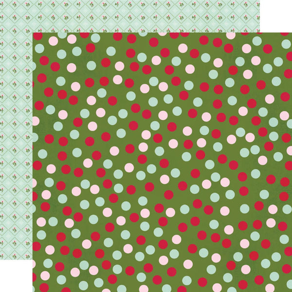 A sheet of patterned paper with a green background covered in red, pink, and mint polka dots, with a second patterned paper layer partially visible behind it in a white and pale green design.