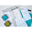 Card-making supplies including ink pads and cards on a white surface