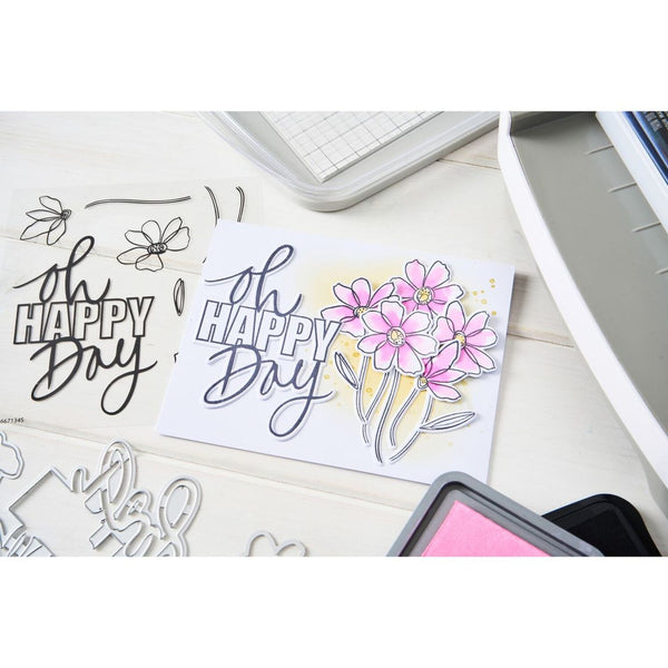 Card with 'Happy Day' text and floral design on a desk with stamping tools.