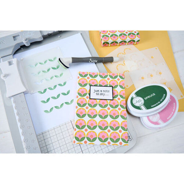 Crafting supplies including patterned paper, stamps, and a stamp pad on a white surface.
