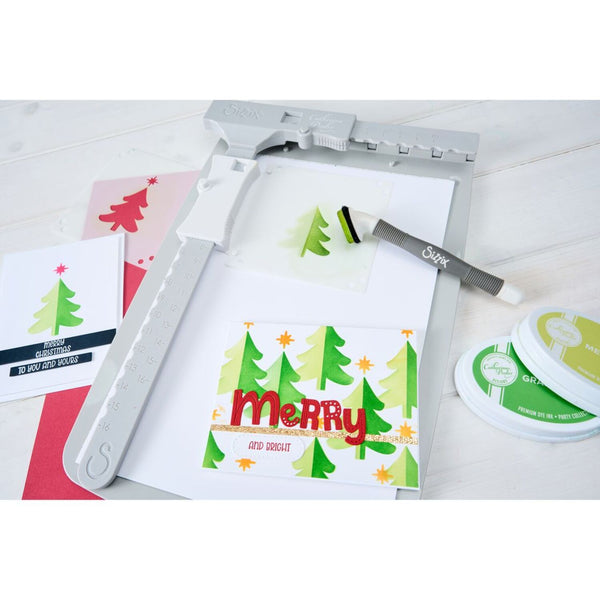 Card making kit with a die-cutting machine, stamps, and printed cards on a white surface.
