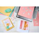 Card-making tools and cards with 'THANKS' and 'LOVE' on a light background