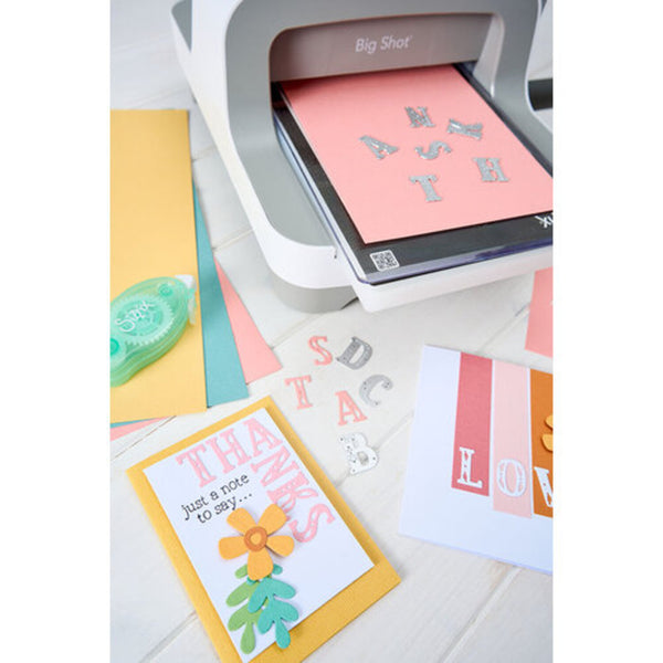 Card making setup with a cutting machine and handmade cards on a white surface