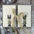 Two handmade greeting cards featuring embossed white backgrounds and soldier nutcracker illustrations, tied with a beige polka-dot ribbon bow. The cards are displayed on a rustic, snowy-textured surface with pine branches, and the text 'NINA STRAUME' is visible in the bottom right corner.