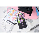 Two greeting cards with colorful text on a white surface with crafting tools.