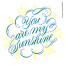 Hand-lettered wall art reading 'You are my sunshine' in flowing blue, green, and purple script with yellow sunburst rays on a white background. Small vertical text at right reads 'Artwork by Melissa Esplin.