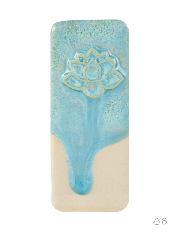 A rectangular ceramic tile featuring a light blue glazed lotus flower design on the upper half and a contrasting beige unglazed lower half, set against a plain white background.