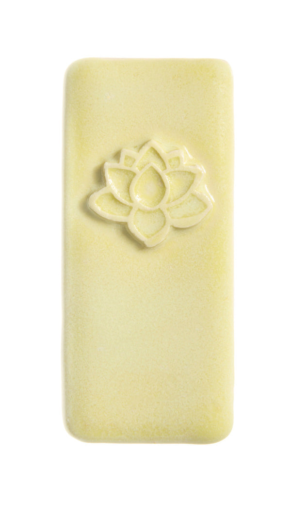 A pale yellow rectangular bar of soap with a raised lotus flower design near the top, shown on a plain white background.