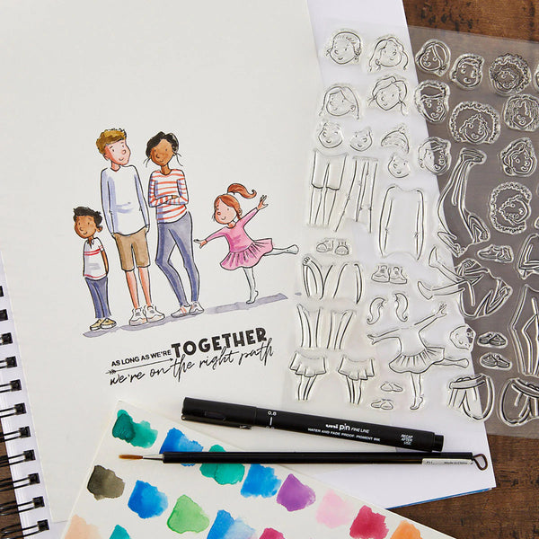 Clear stamps with illustrations of people and objects, a pen, and a color swatch on a wooden surface.