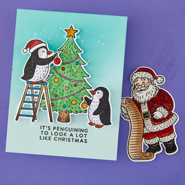 Christmas card with penguins decorating a tree and a Santa Claus sticker on a purple background