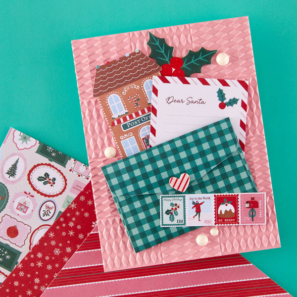 Christmas-themed stationery set with envelopes, postcard, and stamps on a teal background
