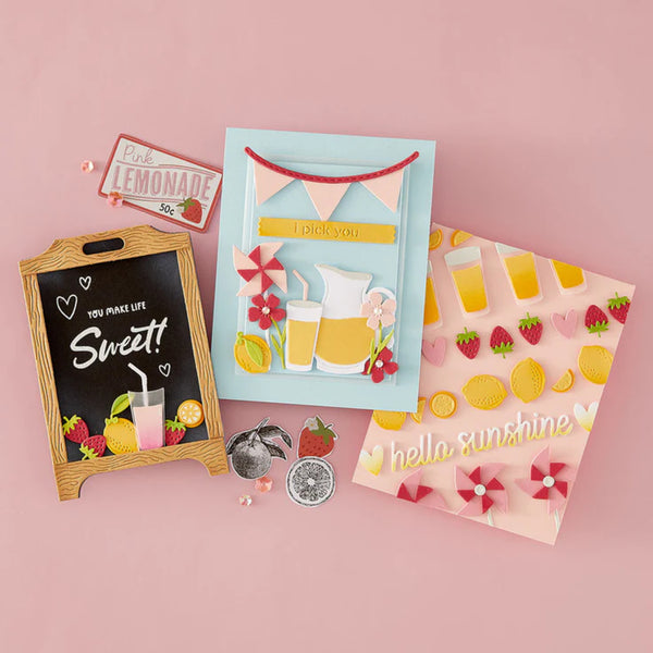 Collection of decorative items including a chalkboard sign, cards, and small figurines on a pink background.