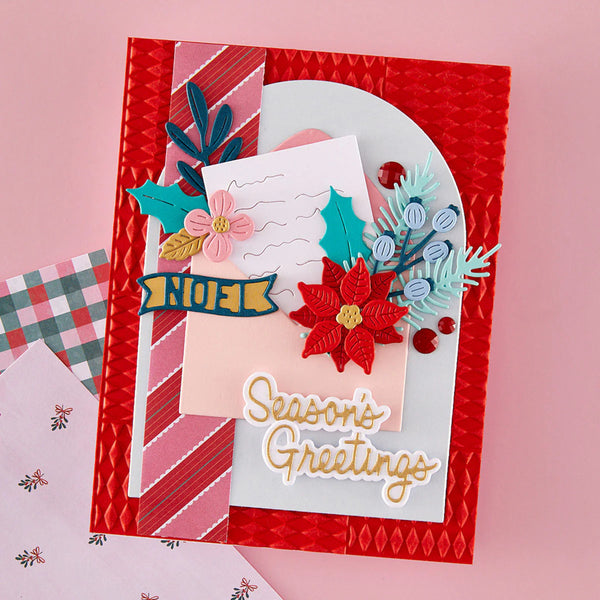 A handmade layered greeting card with a red textured border, pink striped paper, a white arch, and festive embellishments including a red poinsettia, pink flower, teal holly, blue berries, and a yellow banner reading 'Season's Greetings'.