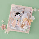 A handmade winter-themed scrapbook or journal page featuring a 3D snowman, layered paper flowers, and a pink textured border, styled on a mint green background with decorative buttons.