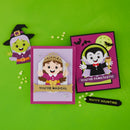 Three handmade Halloween-themed paper cutout cards arranged on a bright green background, including a witch, a princess, and a vampire, with small scattered decorative beads.
